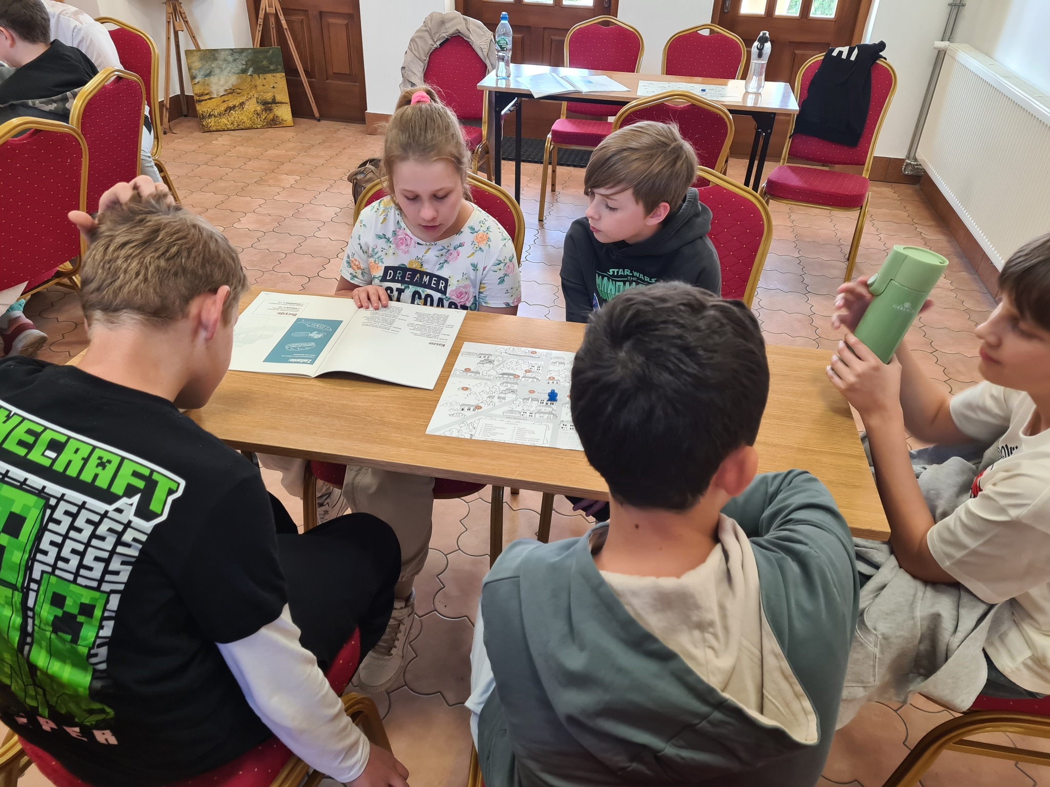 Uczniowie siedzący przy stoliku przeglądający książki