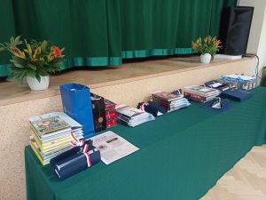 Stół zastawiony nagrodami książkowymi, podziękowaniami, listami gratulacyjnymi i listami pochwalnymi
