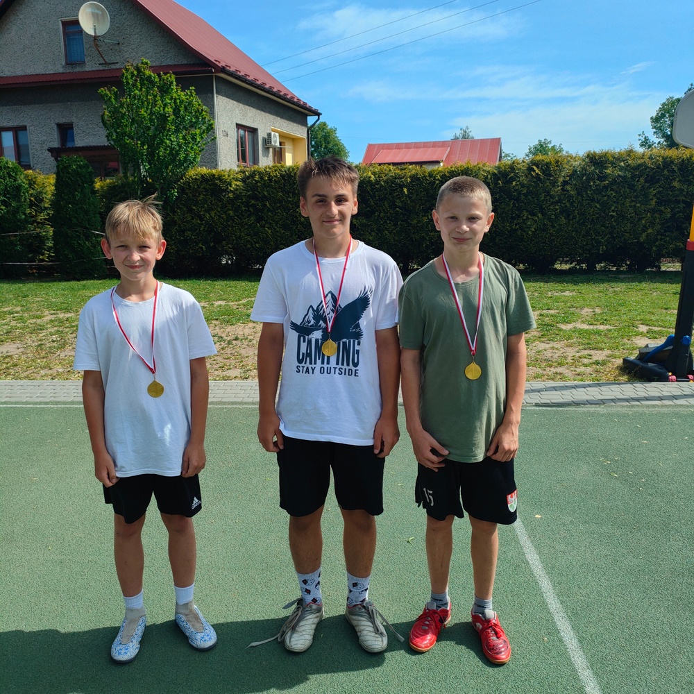 Chłopcy stojący z medalami, którzy zdobyli I miejsce w turnieju piłki nożnej
