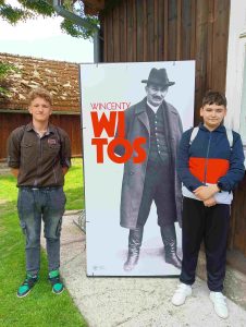Dwóch uczniów stojących przy wizerunku Wincentego Witosa