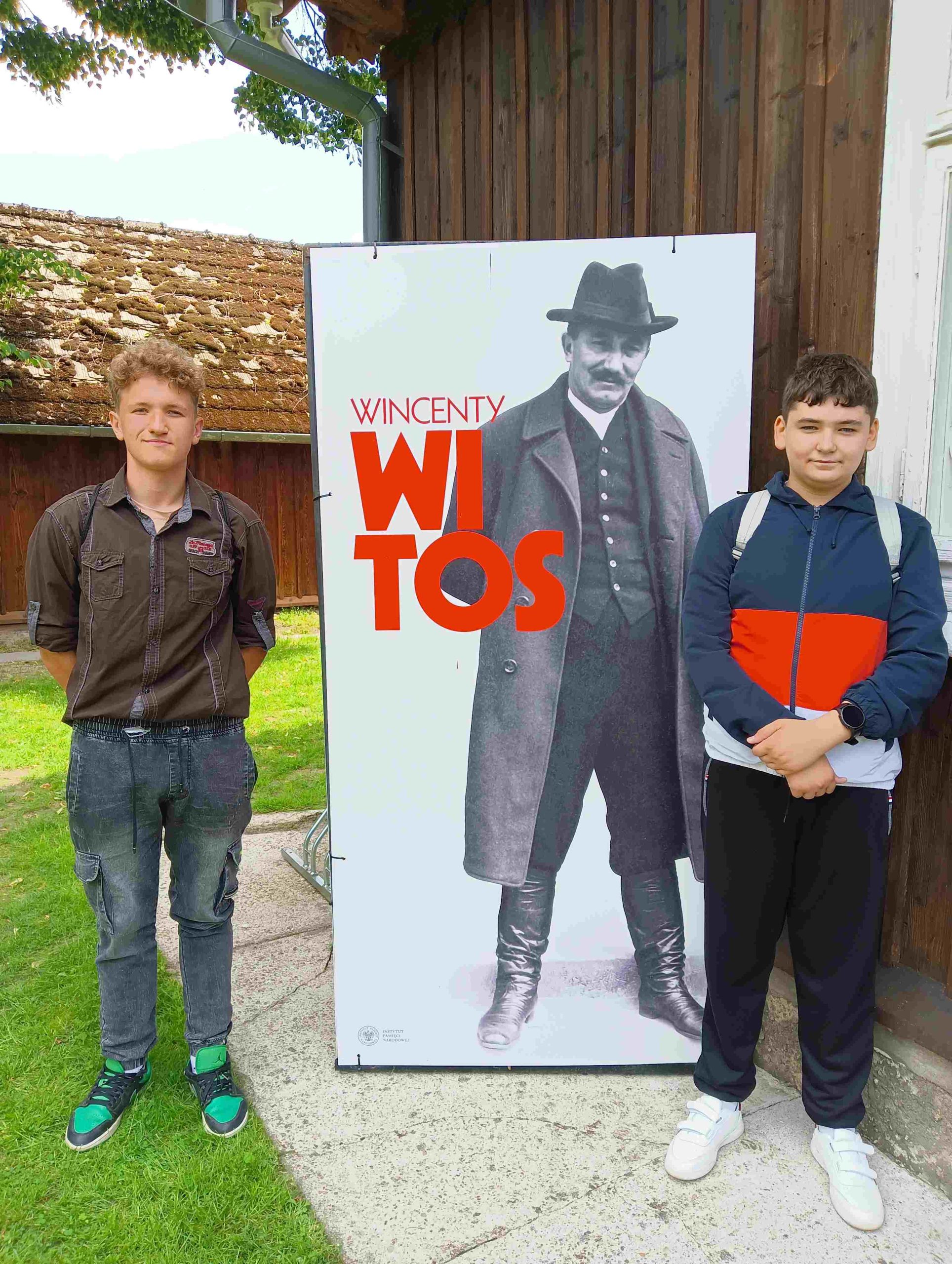 Dwóch uczniów stojących przy wizerunku Wincentego Witosa