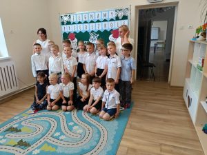 Oddział przedszkolny stojący z dwiema paniami, ubrani na galowo