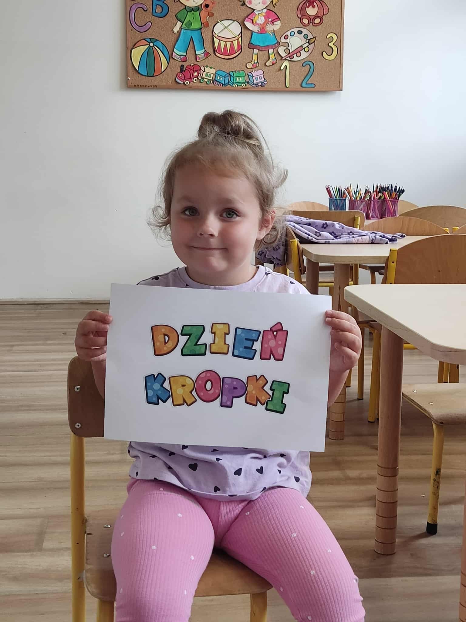 Dziewczynka trzymająca napis Dzień Kropki