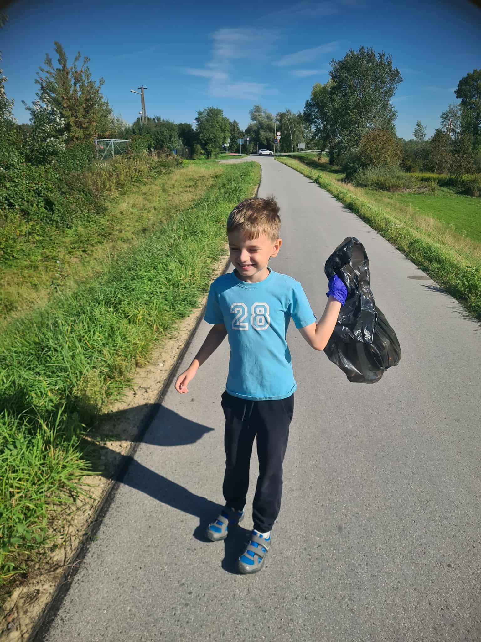 Chłopiec niosący worek ze śmieciami biorący udział w akcji Sprzątanie Świata