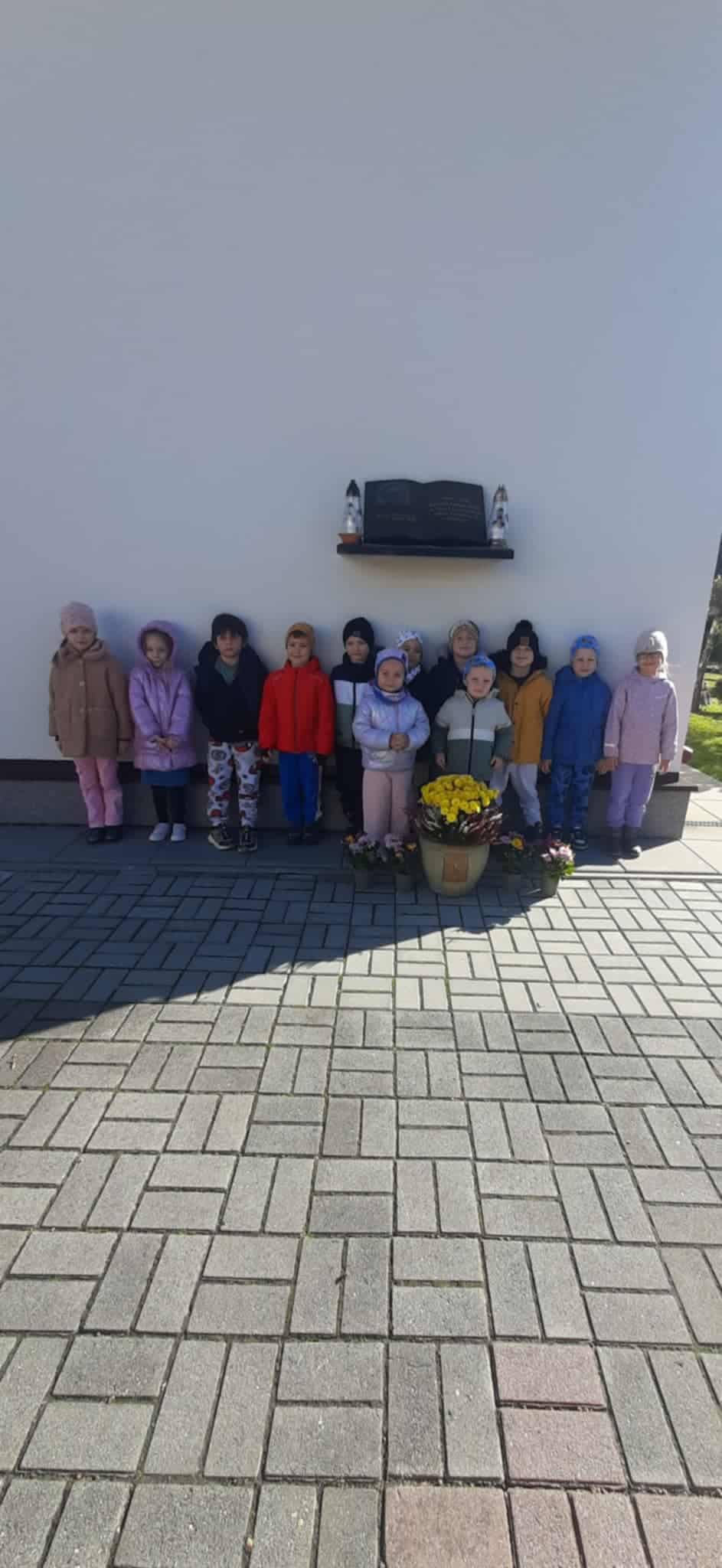 Dzieci stojący przy Tablicy ks. Jana Twardowskiego